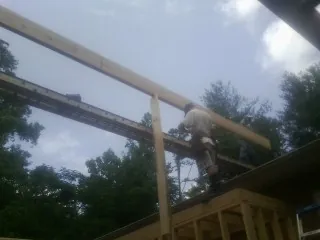 Carpenter setting a ridge beam over a new addition frame — Ice Dam Removal by Roofing Brothers in Iron Gate