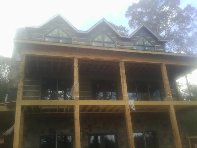 Dormers and porch framing on a large log home under construction — Roof Coating work by our crew in Iron Gate