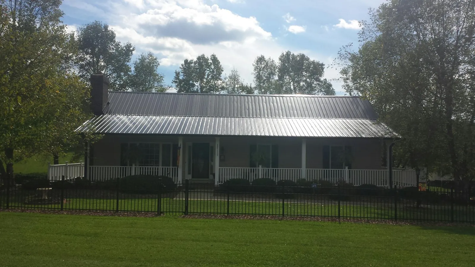 Gray metal roof on a brick ranch with a full width front porch — Gutter Guard Installation work by our crew in Iron Gate