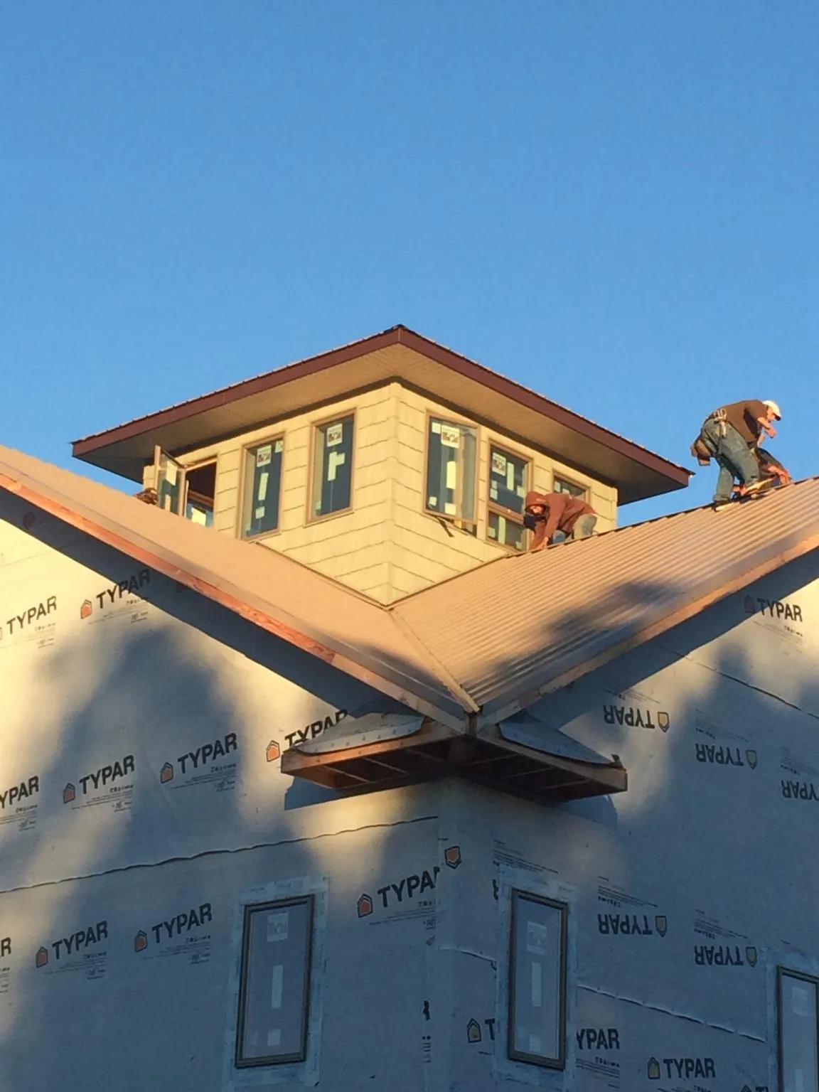 Roofers working around a rooftop cupola on a new metal roof at sunset — Roof Waterproofing in Iron Gate by Roofing Brothers